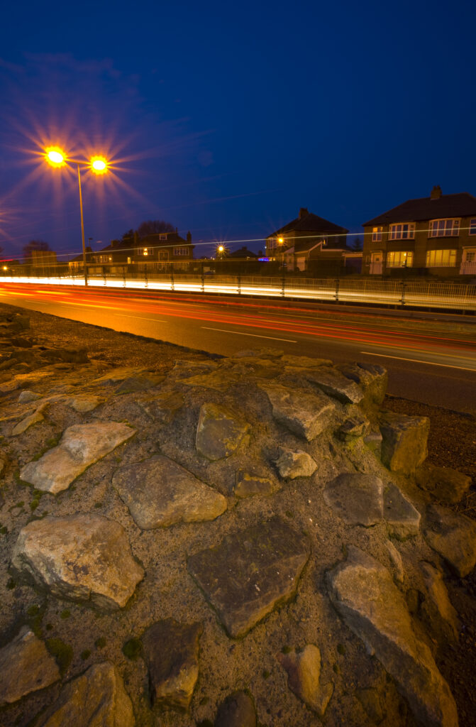 England, Tyne & Wear, Newcastle Upon Tyne. Rush hour traffic alongside Hadrian's Wall in East Denton. Hadrian's Wall was built to protect Roman Britain from raids by the Picts to the north, and stretched from the Solway Firth to Wallsend in North Tyneside.