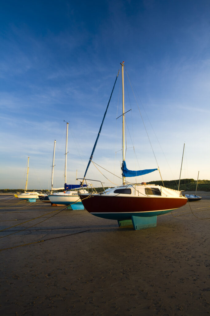England, Northumberland, Beadnell. Small sailing boats moored in Beadnell Bay - viewed at low tide.