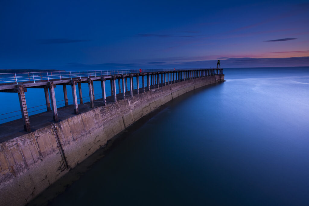 England, North Yorkshire, Whitby. One of the entrance piers of Whitby Harbour at dawn.
