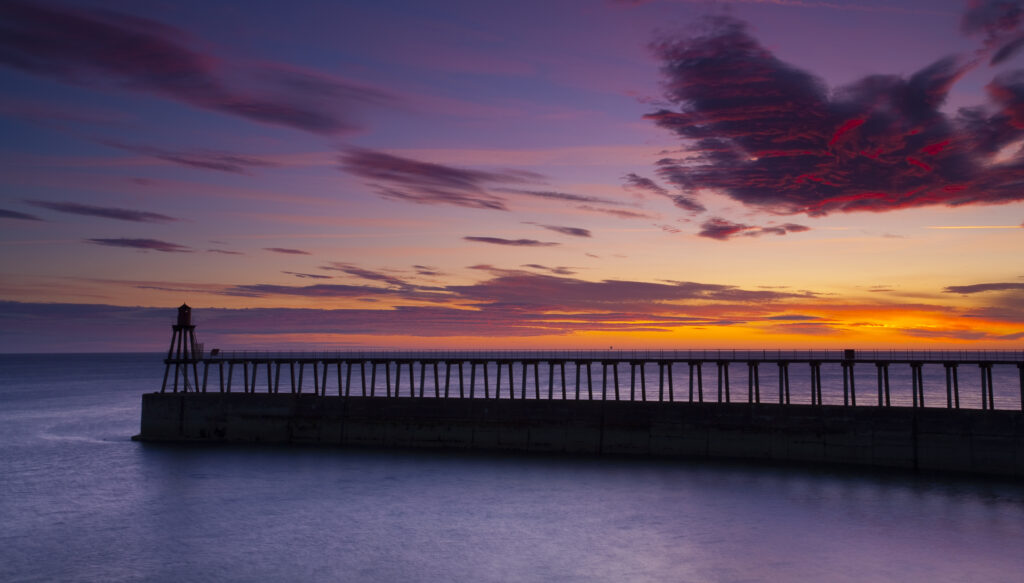 England, North Yorkshire, Whitby. One of the entrance piers of Whitby Harbour at dawn.