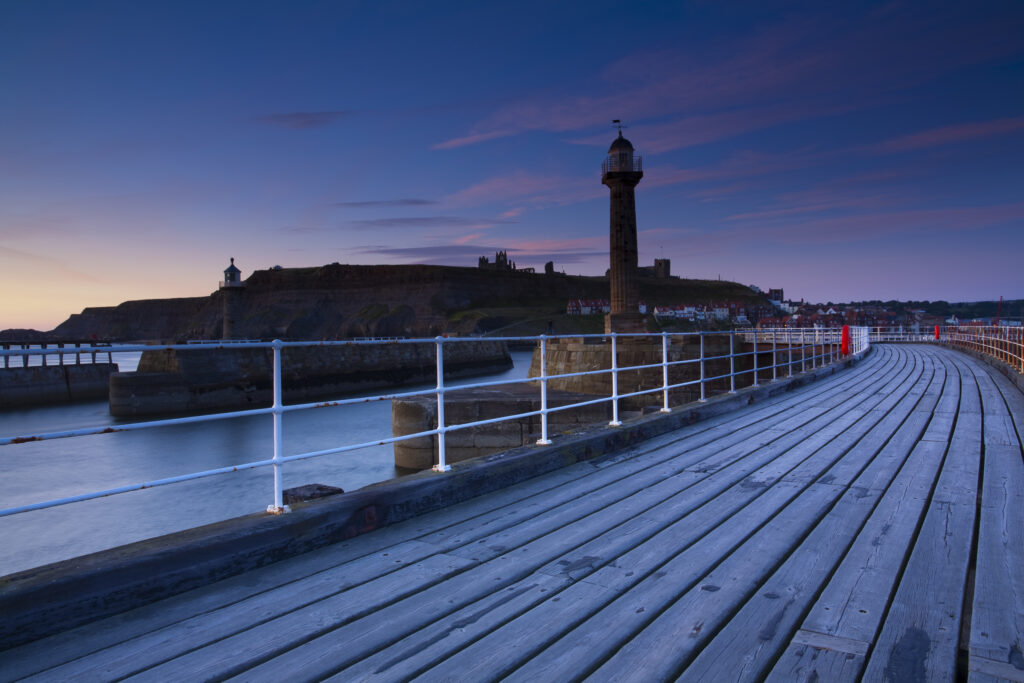 England, North Yorkshire, Whitby. Looking from the entrance piers of Whitby Harbour at dawn.
