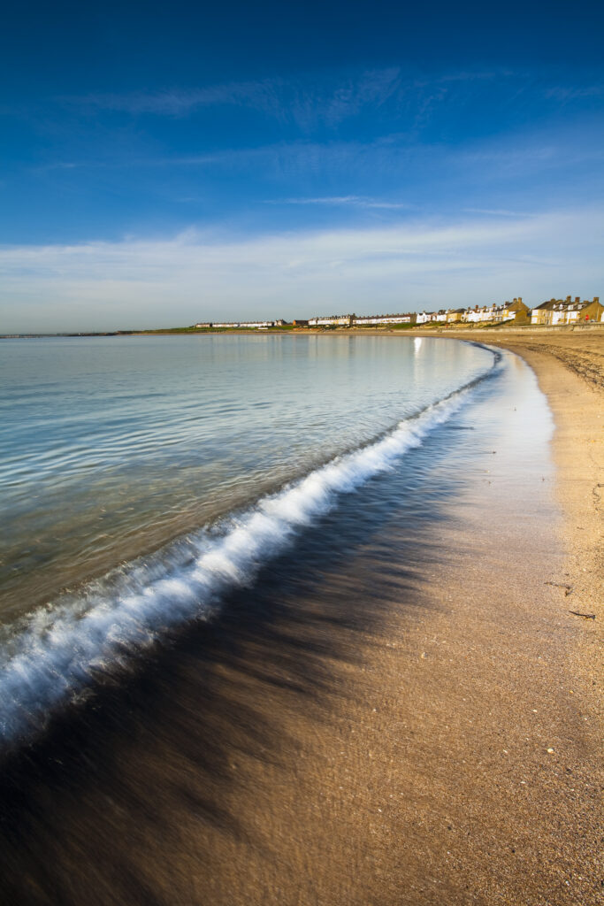 England, Northumberland, Newbiggin by the sea. Coal dust revealed by a retreating wave on the Newbiggin by the sea beach.