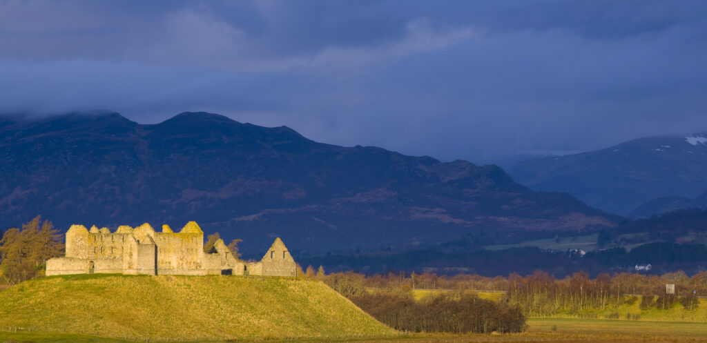 Scotland, Scottish Highlands, Cairngorms National Park. Dramatic light bathes the Ruthven Barracks, with the Monadhliath Mountains overlooking the ruins.