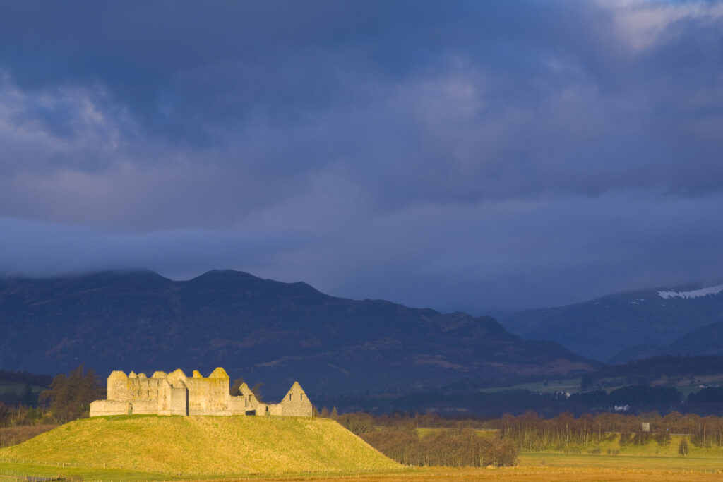 Scotland, Scottish Highlands, Cairngorms National Park. Dramatic light bathes the Ruthven Barracks, with the Monadhliath Mountains overlooking the ruins.
