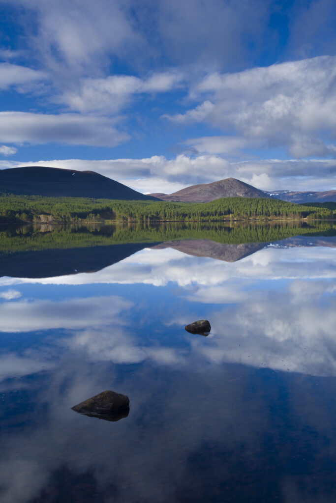 Scotland, Scottish Highlands, Cairngorms National Park. Clouds, forest and mountains reflected upon the still waters of Loch Morlich.