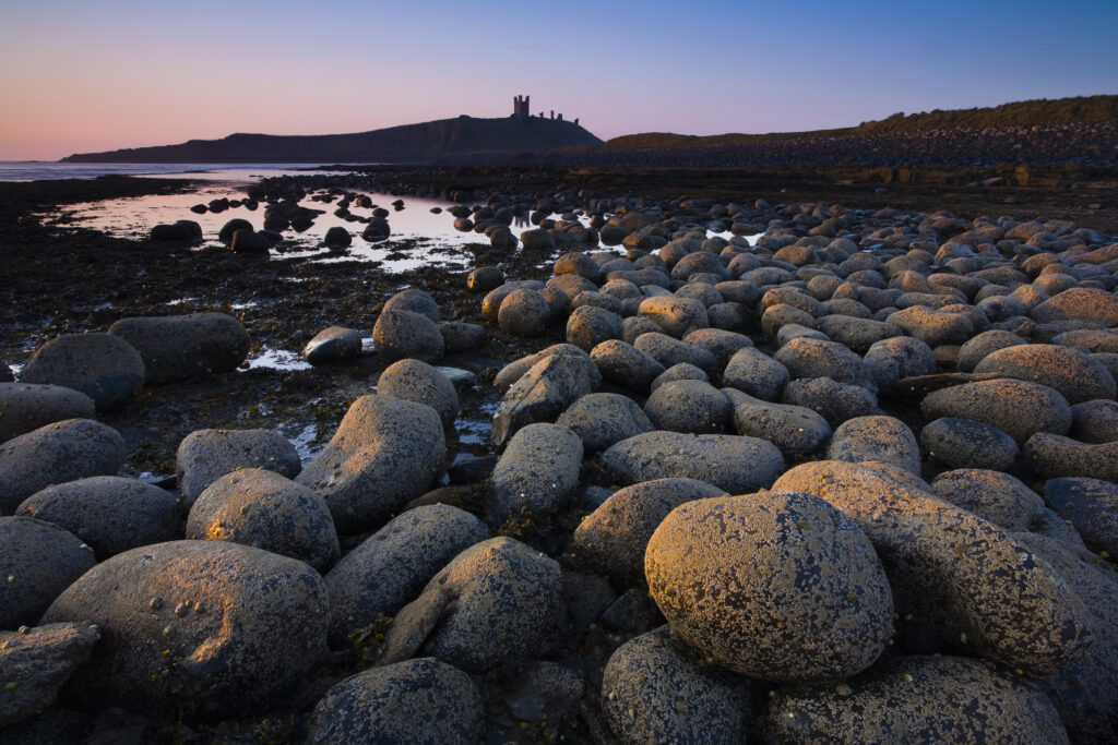 England, Northumberland, Embleton Bay. Weathered rocks dominate the low-tide shoreline of Embleton Bay
