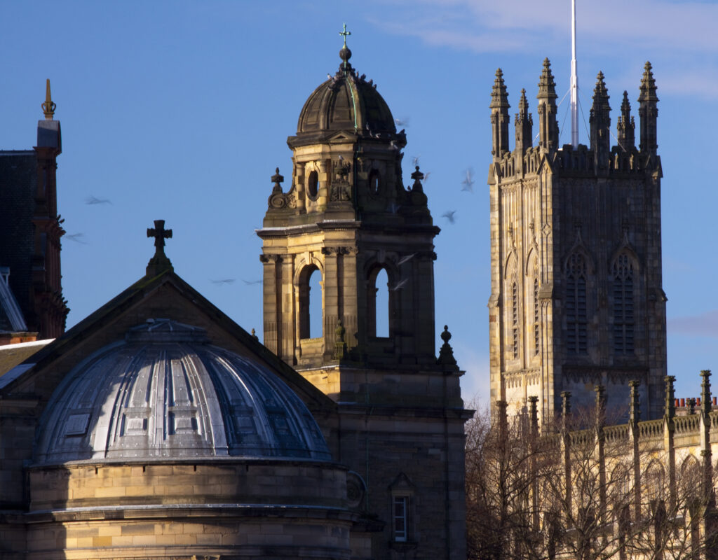 Scotland, Edinburgh, Edinburgh City. Birds flock around the Saint Cuthberts Parish Church and the gothic style Church of St John the Evangelist.