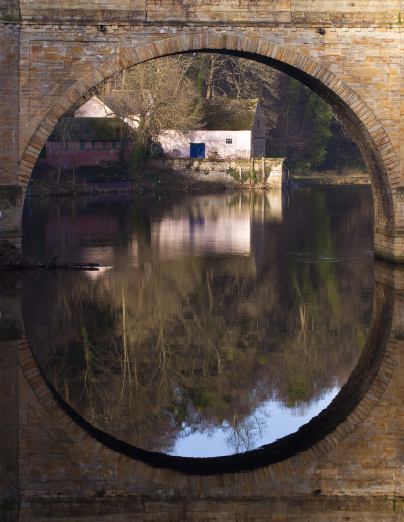 England, County Durham, Durham City. Archway of South Bailey Bridge, reflected upon the River Wear.