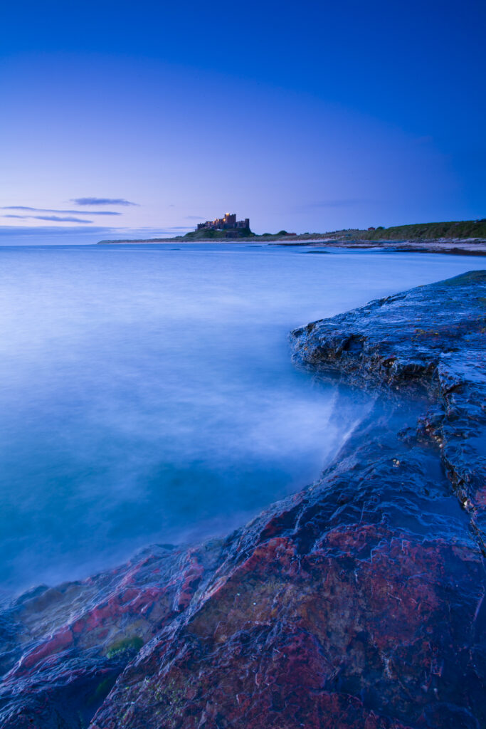England, Northumberland, Bamburgh. Bamburgh Castle and the North Sea, viewed from Harkess Rocks.
