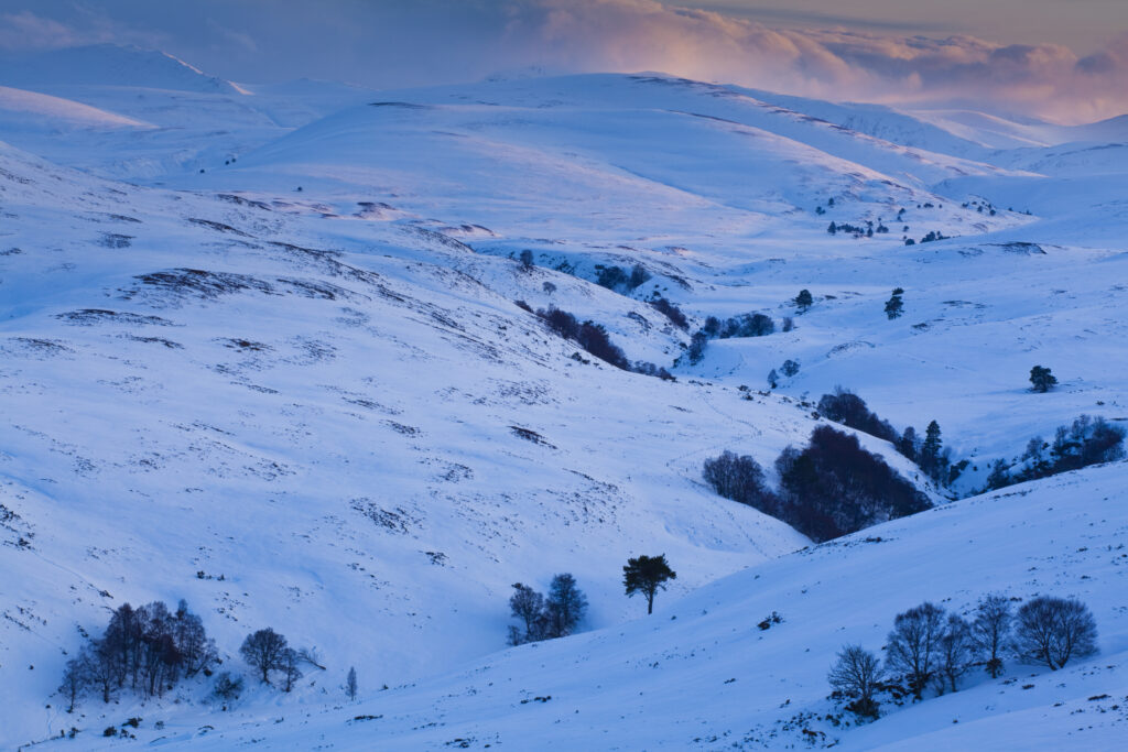 Scotland, Scottish Highlands, Cairngorms National Park. View from the the Old Military Road (now part of the A939) from near the Bridge of Brown looking across a snow covered valley towards the mountain peaks of the Cairngorms National Park.