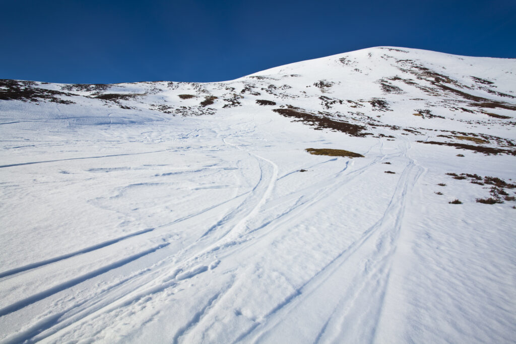 Scotland, Perthshire, Glenshee. Ski and snowboard tracks on the snow covered slopes of the Glenshee Ski Area.