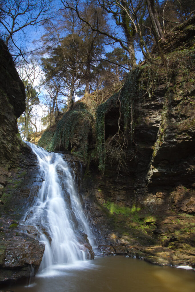 England, Northumberland, Hareshaw Linn. Hareshaw Linn is a spectacular waterfall located in a steep sided gorge, which continues to flow through a wooded valley. Hareshaw Linn is located near Bellingham within the Northumberland National Park.