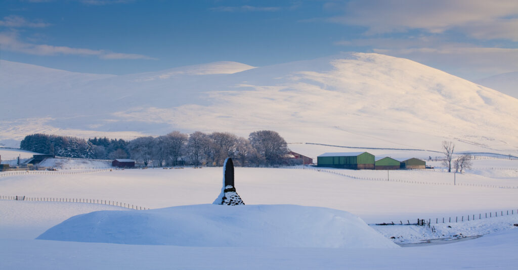 Scotland, South Lanarkshire, Clyde Valley. A monument in honour of Matthew McKenorick, a former postmaster from Abington in Clydesdale, under the shadow of the snow covered Clyde Valley hills.