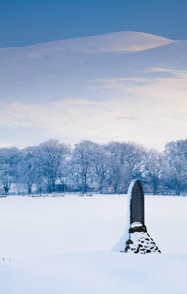Scotland, South Lanarkshire, Clyde Valley. A monument in honour of Matthew McKenorick, a former postmaster from Abington in Clydesdale, under the shadow of the snow covered Clyde Valley hills.