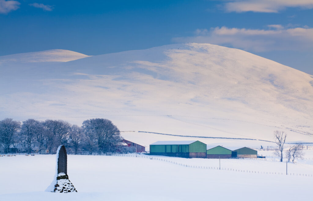 Scotland, South Lanarkshire, Clyde Valley. A monument in honour of Matthew McKenorick, a former postmaster from Abington in Clydesdale, under the shadow of the snow covered Clyde Valley hills.