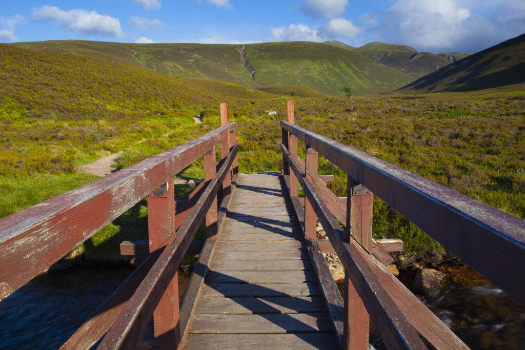 Scotland, Scottish Highlands, Cairngorms National Park. Footbridge crossing a mountain burn flowing through the wild landscape to be found near Strath Nethy.