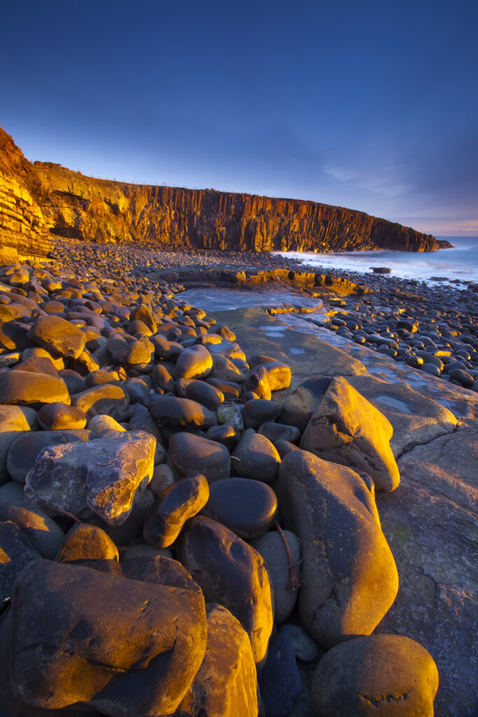 England, Northumberland, Cullernose Point. Dawn light illuminates the rocky shoreline of Cullernose Point, near the village of Craster on the Northumberland Heritage Coast.
