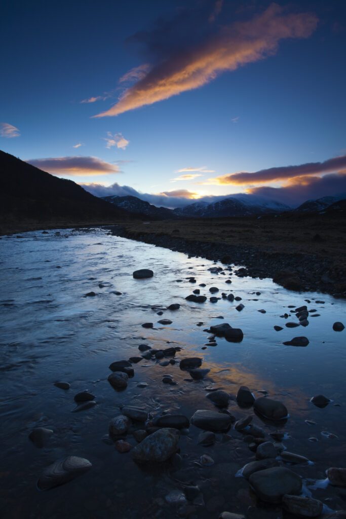 Scotland, Scottish Highlands, Cairngorms National Park. Clouds at sunset reflected upon the still waters of the River Calder running through Glen Banchor near Newtonmore and the Monadhliath Mountains.