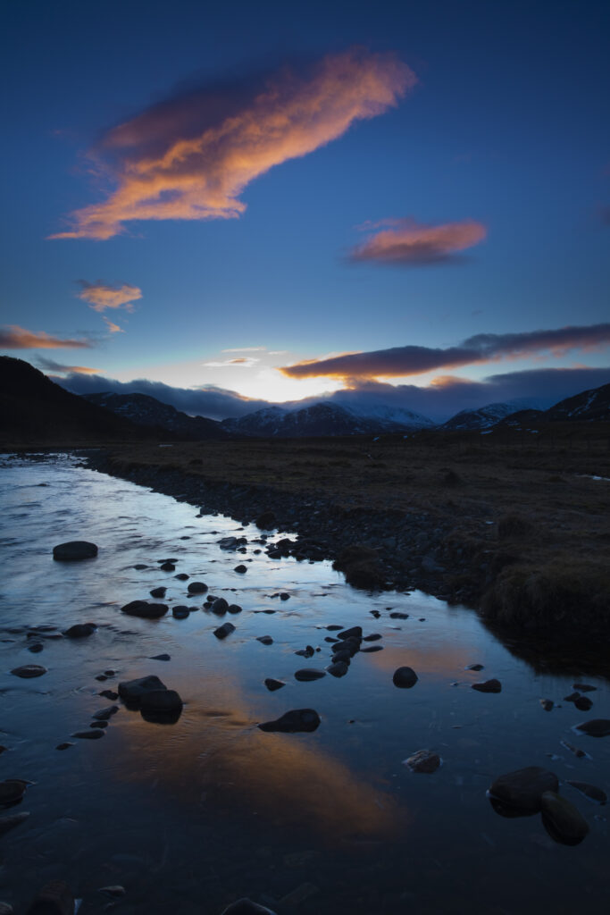 Scotland, Scottish Highlands, Cairngorms National Park. Clouds at sunset reflected upon the still waters of the River Calder running through Glen Banchor near Newtonmore and the Monadhliath Mountains.