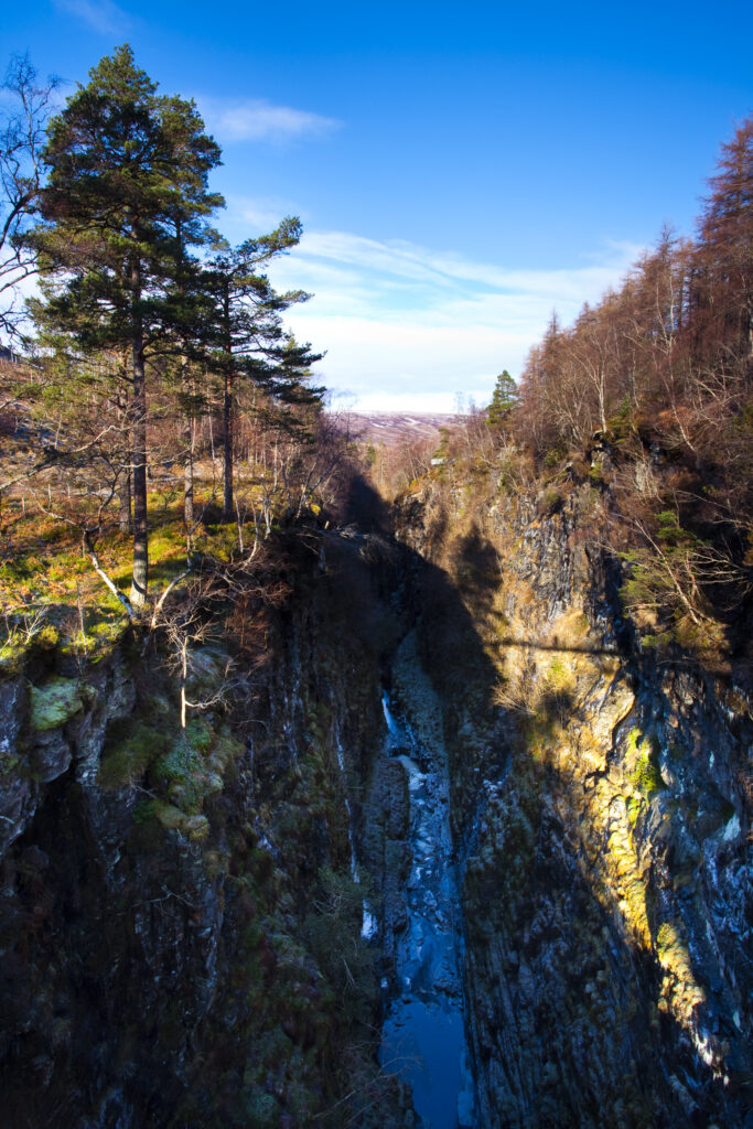 Scotland, Scottish Highlands, Corrieshalloch Gorge. The Corrieshalloch Gorge is a spectacular mile-long gorge created by the River Droma which has carved the canyon by eroding through hard metamorphic rock.
