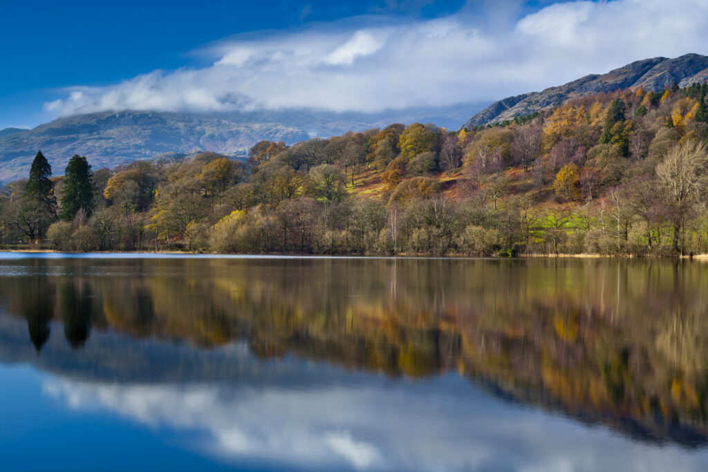 England, Cumbria, Lake District National Park. Lakeland hills reflected upon the still face of Coniston Water.