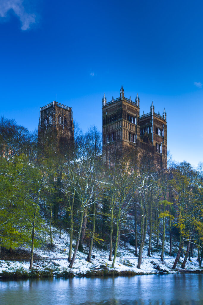 England, County Durham, Durham City. Durham Cathedral, situated above the snow covered river banks of the River Wear.
