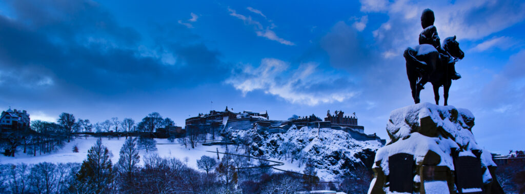 Scotland, Edinburgh, Edinburgh City. Monument on Princes Street erected in memory of the Royal Scots Greys, over looking Edinburgh Castle and Princes Garden under a blanket of snow.