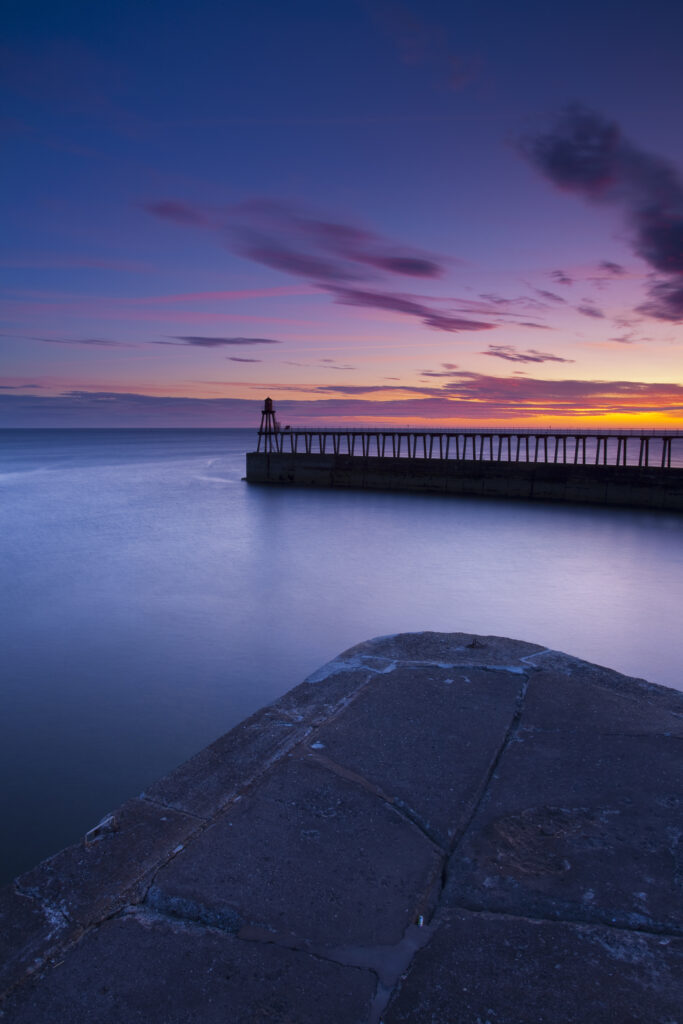 England, North Yorkshire, Whitby. One of the entrance piers of Whitby Harbour at dawn.