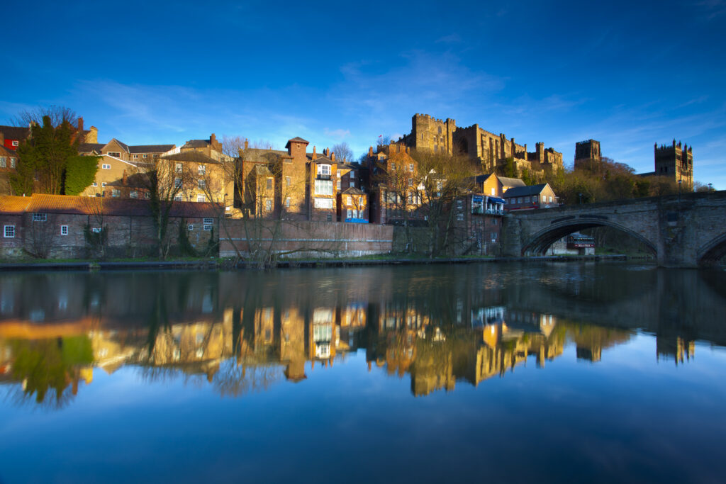 England, County Durham, Durham City. Bridge over the River Wear in the city of Durham, with Durham Castle, Cathedral and city reflected upon the still water face.