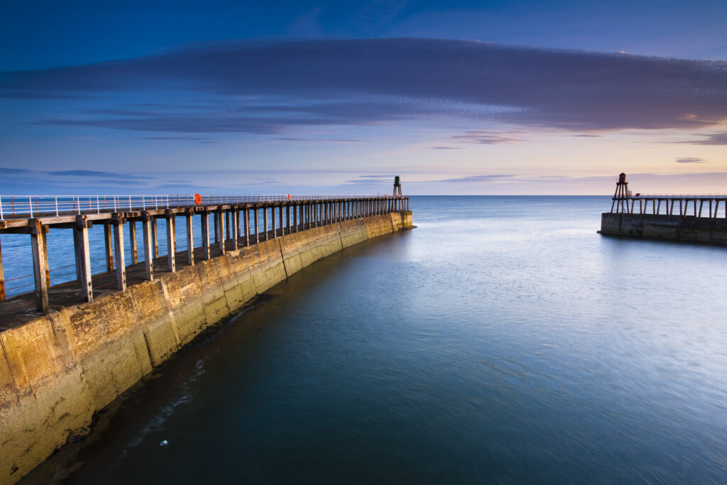 England, North Yorkshire, Whitby. The entrance piers of Whitby Harbour shortly after dawn.