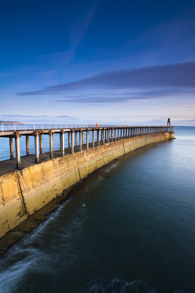 England, North Yorkshire, Whitby. The entrance piers of Whitby Harbour shortly after dawn.