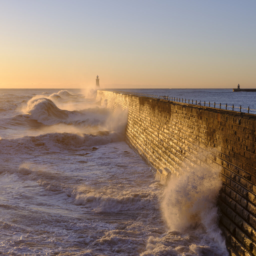 England, Tyne and Wear, Tynemouth. Waves crash on the North Pier at the mouth of the River Tyne.
