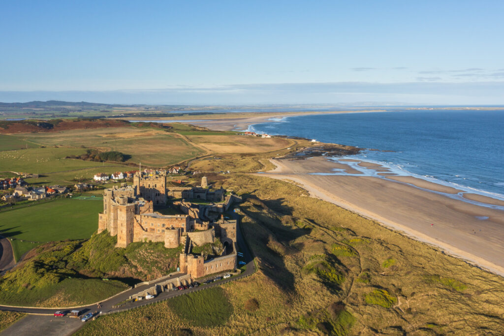 England, Northumberland, Bamburgh. Aerial photo of early morning light on the Northumberland Heritage Coast and Bamburgh Castle.