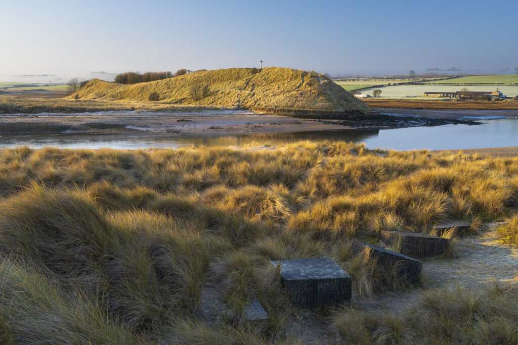 England, Northumberland, Alnmouth. Sand dune and war defences near the Aln estuary near Alnmouth with Church Hill in the distance.