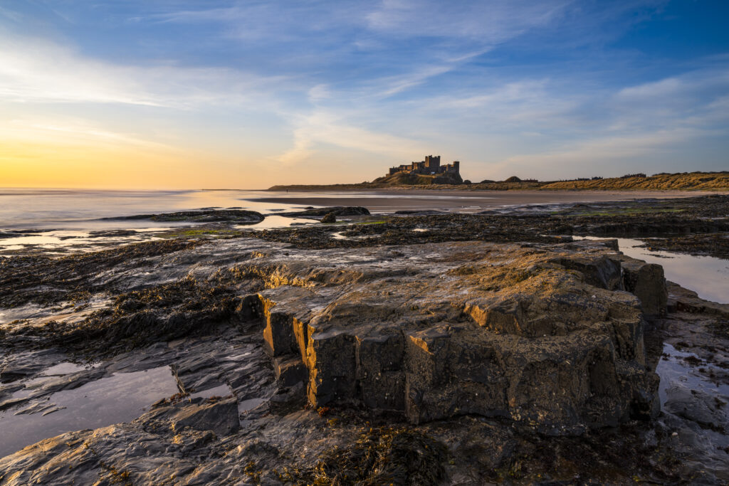 England, Northumberland, Bamburgh. Early morning light on the Northumberland Heritage Coast overlooked by Bamburgh Castle.