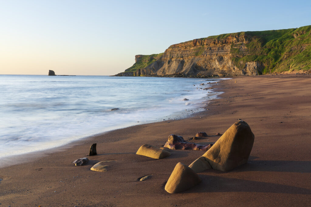 England, North Yorkshire, North York Moors National Park. Early morning light at Saltwick Bay and Nab near Whitby.
