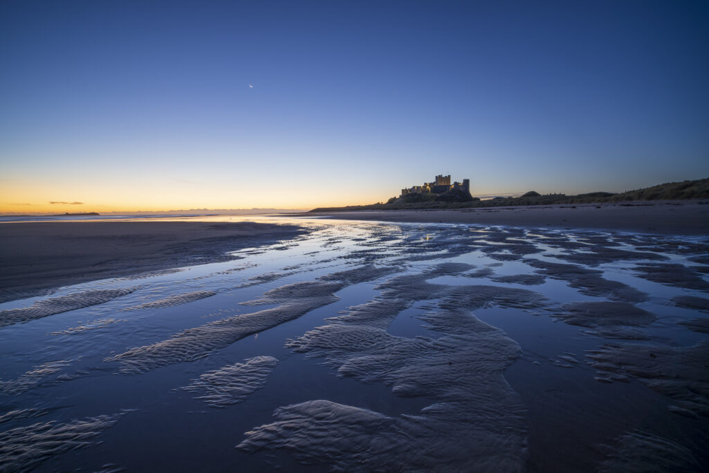 England, Northumberland, Bamburgh. Pre-dawn colours on the Northumberland Heritage Coast overlooked by Bamburgh Castle.