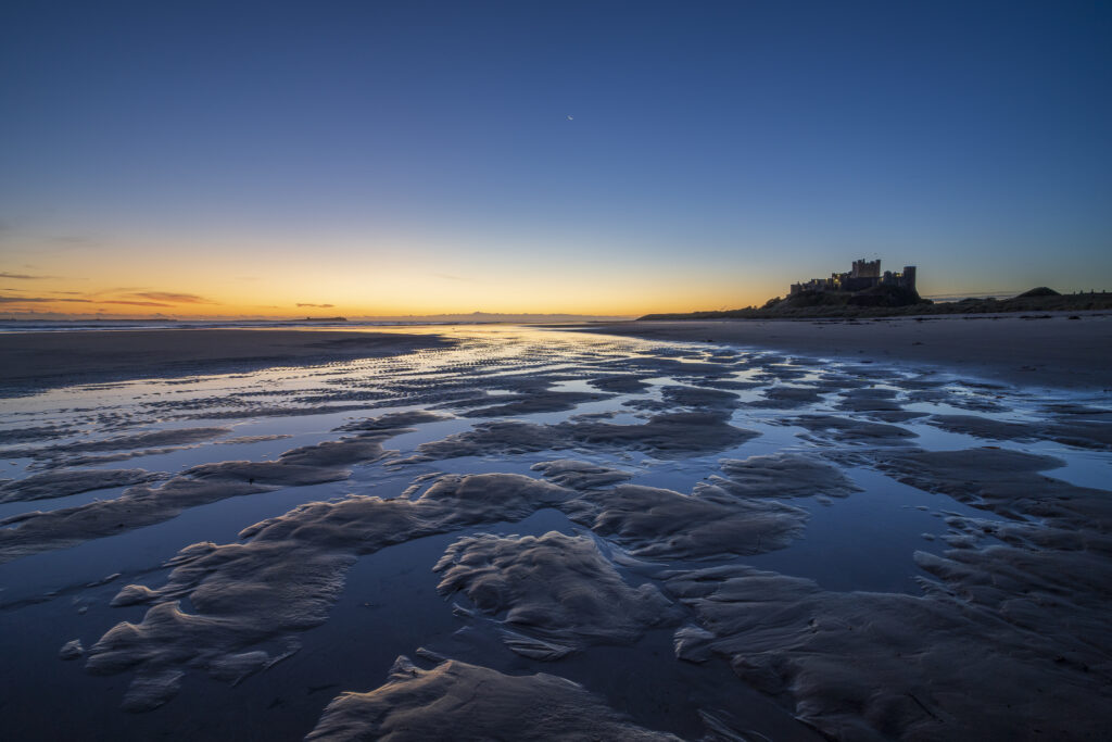 England, Northumberland, Bamburgh. Pre-dawn colours on the Northumberland Heritage Coast overlooked by Bamburgh Castle.