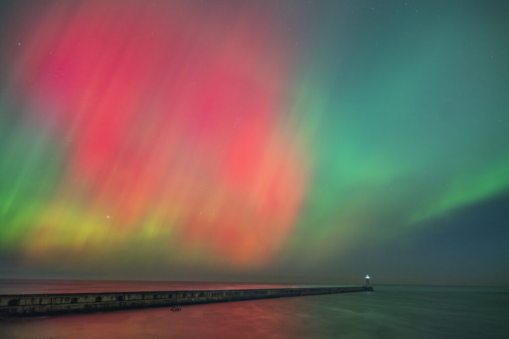 England, Tyne and Wear, Tynemouth. The Northern lights (aurora borealis) viewed near Tynemouth Pier.