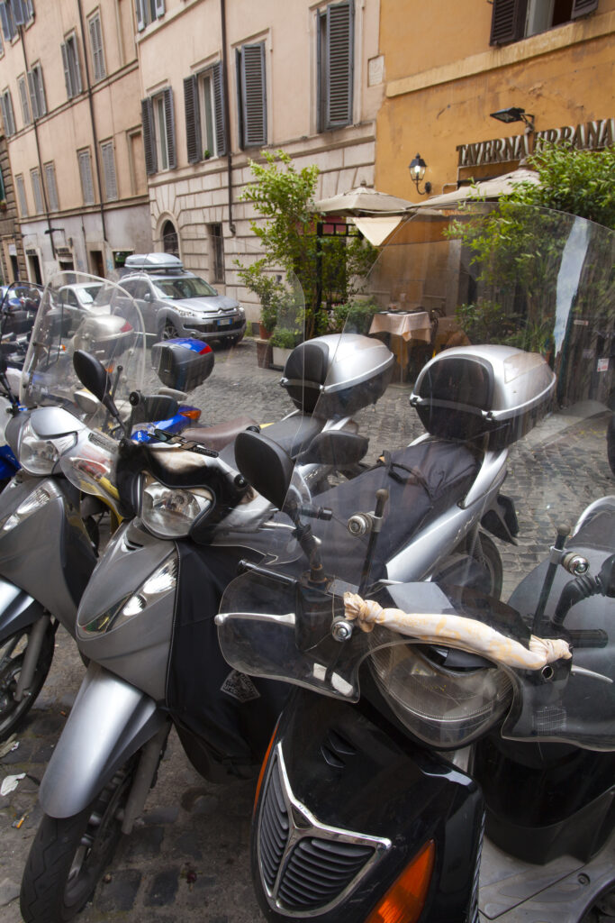 Italy, Lazio, Rome. Mopeds and scooters parked outside a typical Rome restaurant in the city of Rome.