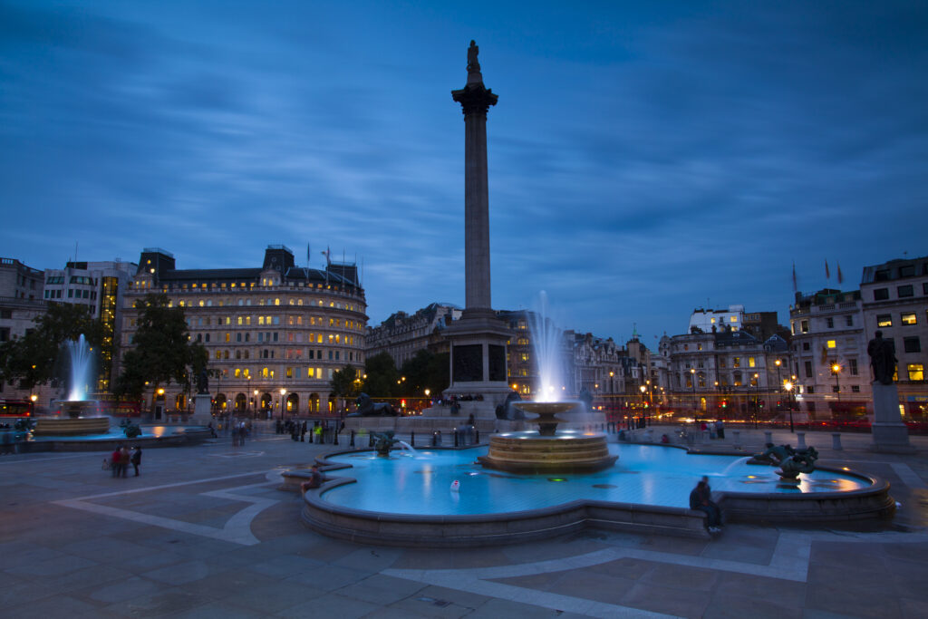 England, Greater London, City of Westminster. Nelson’s Column and nearby fountains in Trafalgar Square, a popular tourist destination in London, photographed at dusk.