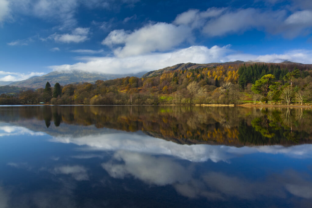England, Cumbria, Lake District National Park. Lakeland hills reflected upon the still face of Coniston Water.