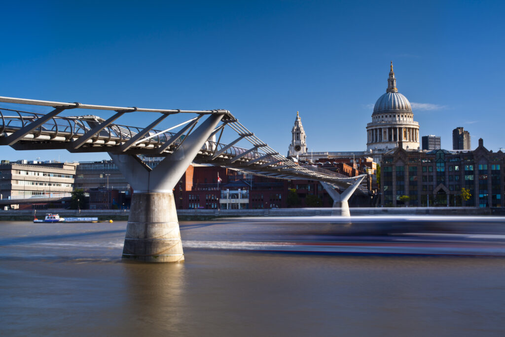 England, London, St Pauls Cathedral. A boat passes below the London Millennium Bridge which links the south bank of the Thames with St Pauls Cathedral and the city.