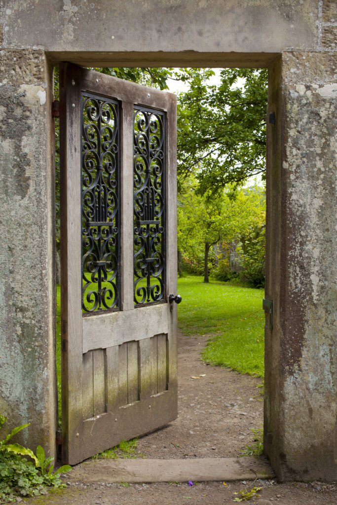 England, Northumberland, Wallington Hall Walled Garden. Stone doorway with open door leading into the Wallington Walled Garden - A National Trust Property.