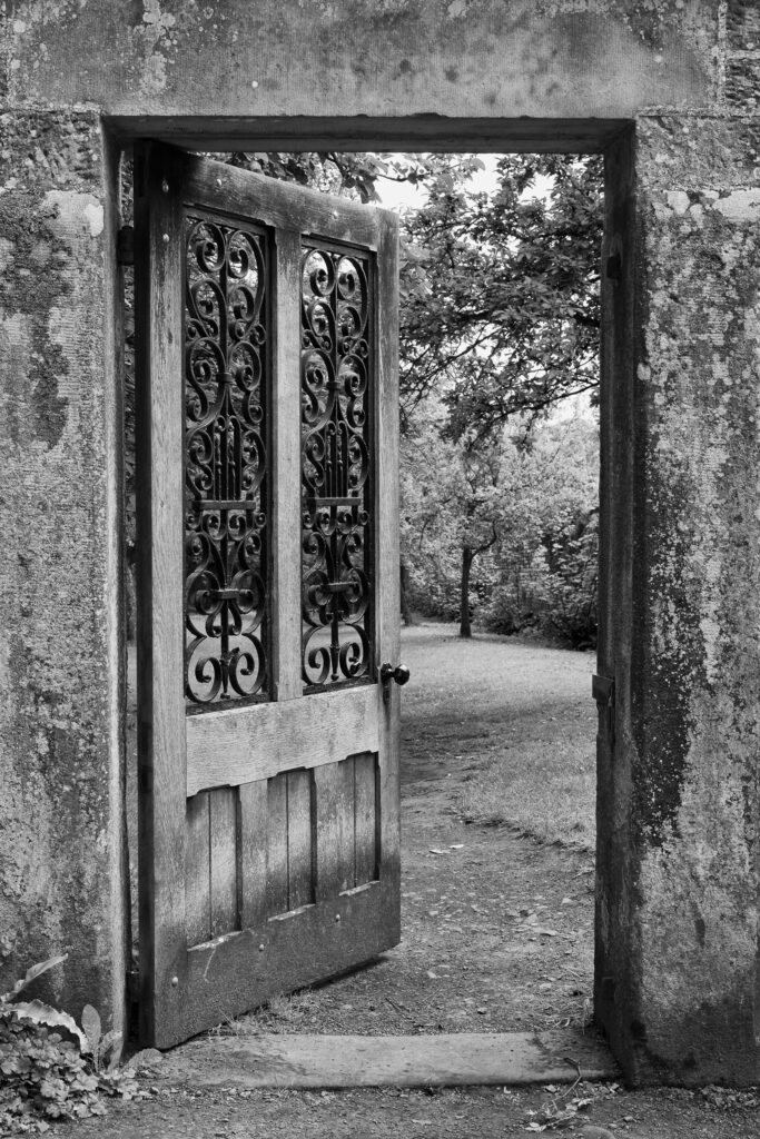 England, Northumberland, Wallington Hall Walled Garden. Stone doorway with open door leading into the Wallington Walled Garden - A National Trust Property.