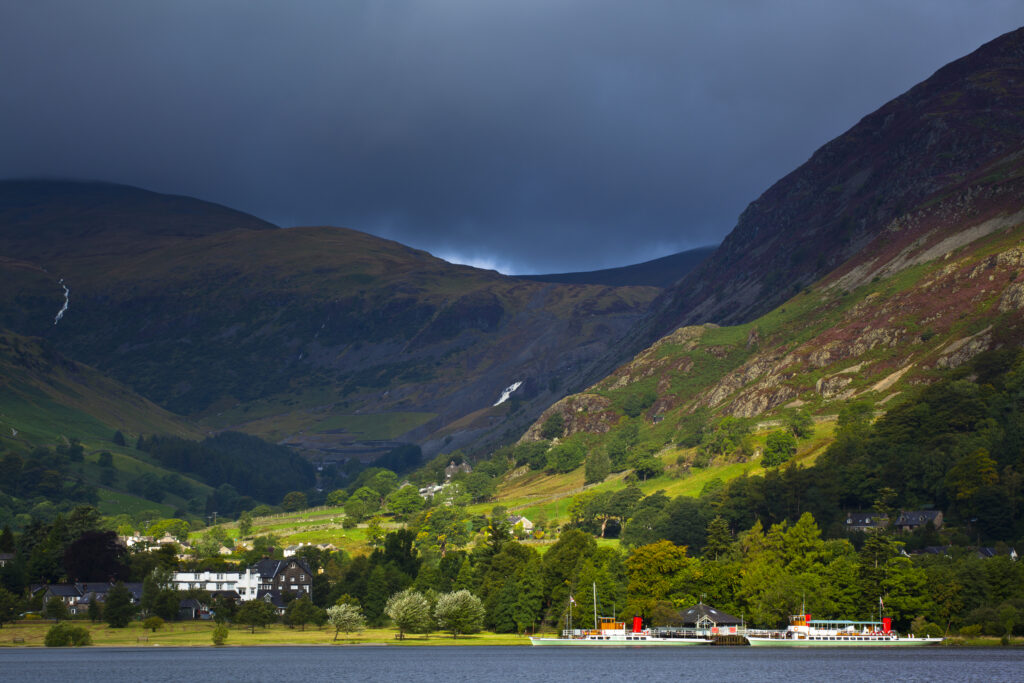 England, Cumbria, Lake District National Park. Breaking light on Steamers moored at Glenridding in Patterdale with lakeland fells in the distance.
