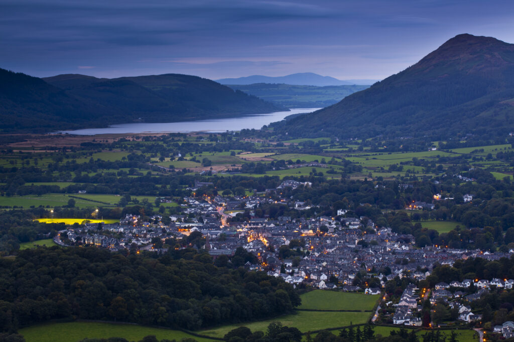 England, Cumbria, Lake District National Park. The popular lakeland village, Keswick, with Bassenthwaite in the distance, viewed at dusk.