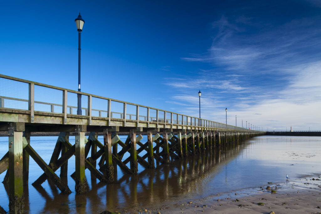 England, Northumberland, Amble. Amble Pier, alongside Amble Harbour. Amble is a small fishing village located along the Northumberland Heritage Coast.