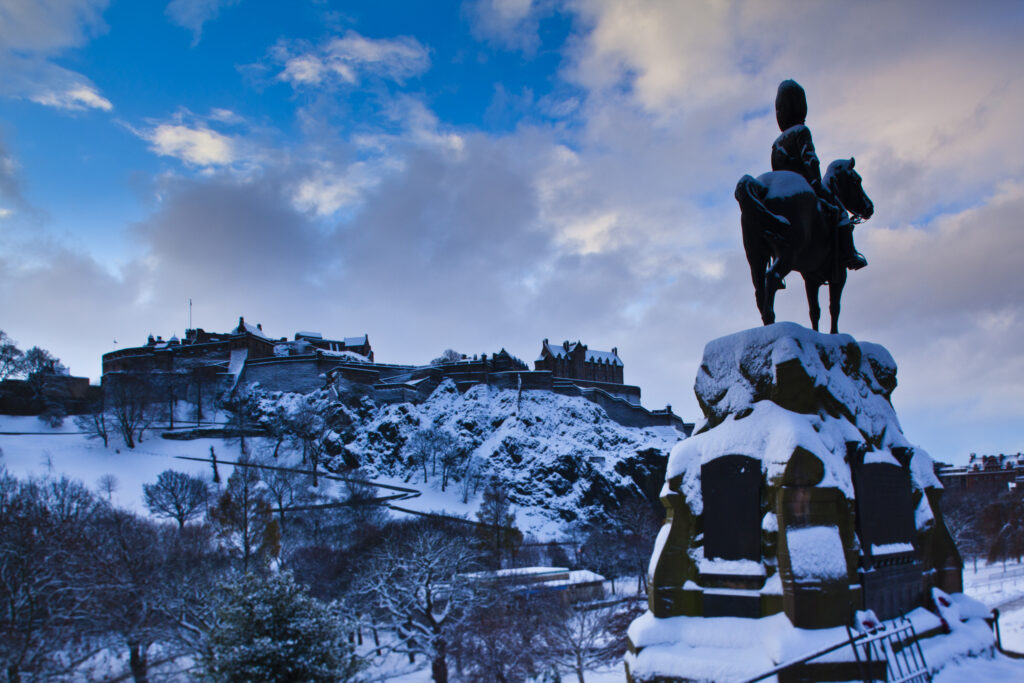 Scotland, Edinburgh, Edinburgh City. Monument on Princes Street erected in memory of the Royal Scots Greys, over looking Edinburgh Castle and Princes Garden under a blanket of snow.