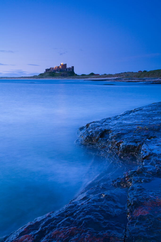 England, Northumberland, Bamburgh. Bamburgh Castle and the North Sea, viewed from Harkess Rocks.